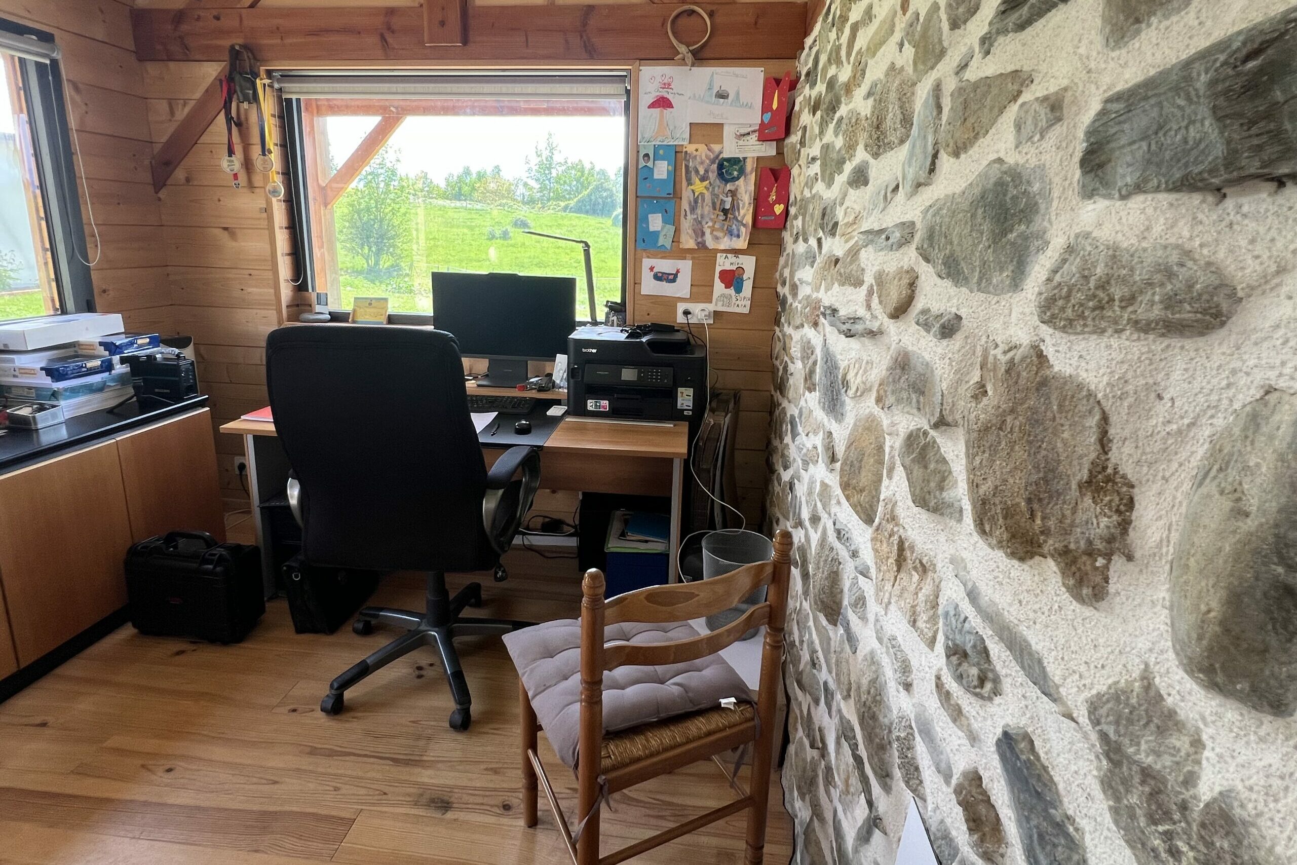 Espace de bureau de l'agence La Clé des Pyrénées à Argelès-Gazost, avec charpente en bois apparente et mur en pierre