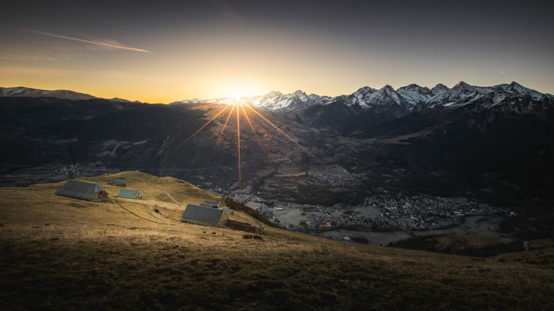 Vue plongeante sur la vallée de Saint-Lary-Soulan au coucher du soleil avec granges d'estive et sommets enneigés