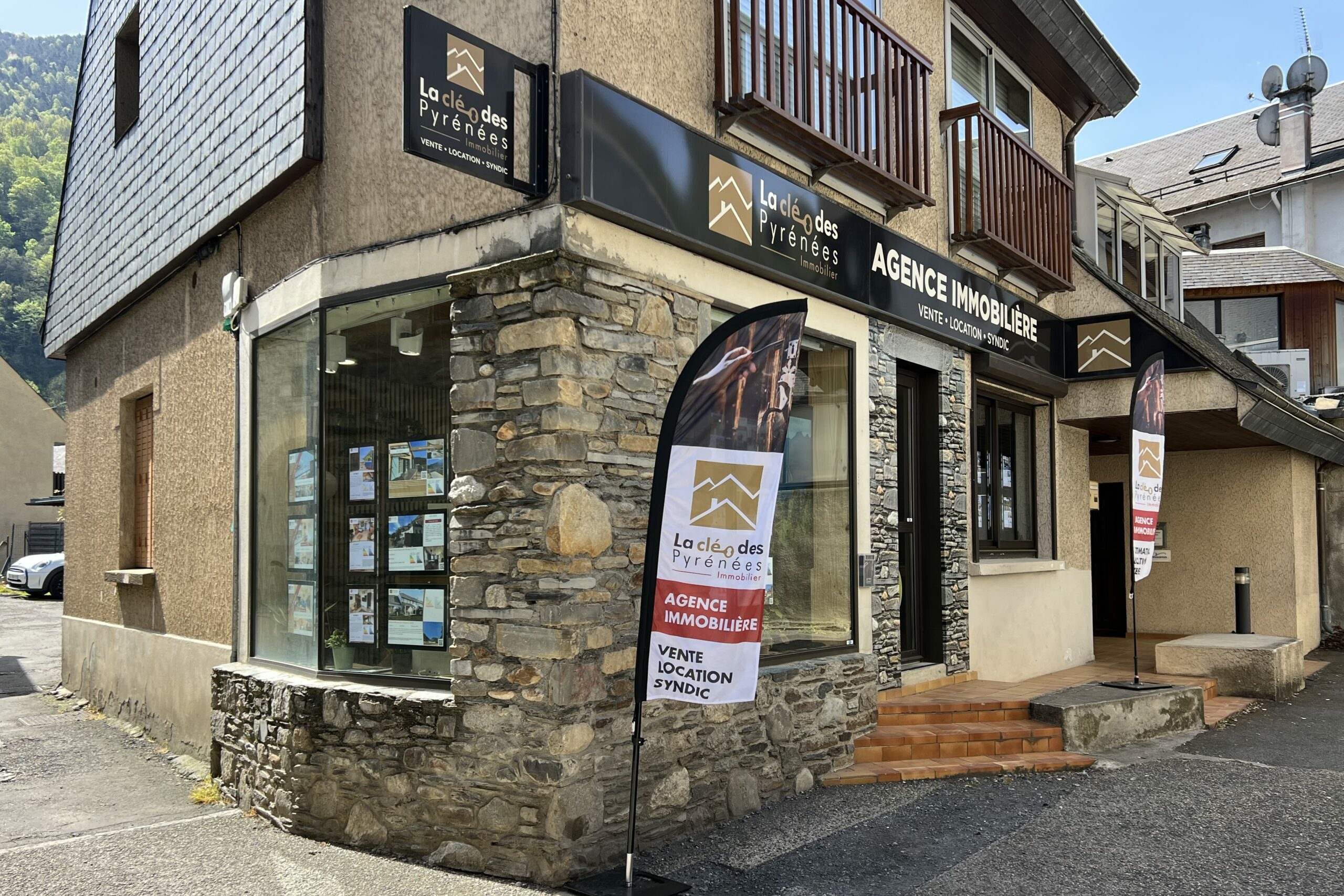 Devanture de l'agence immobilière La Clé des Pyrénées à Saint-Lary-Soulan, façade en pierre avec vitrine d'annonces