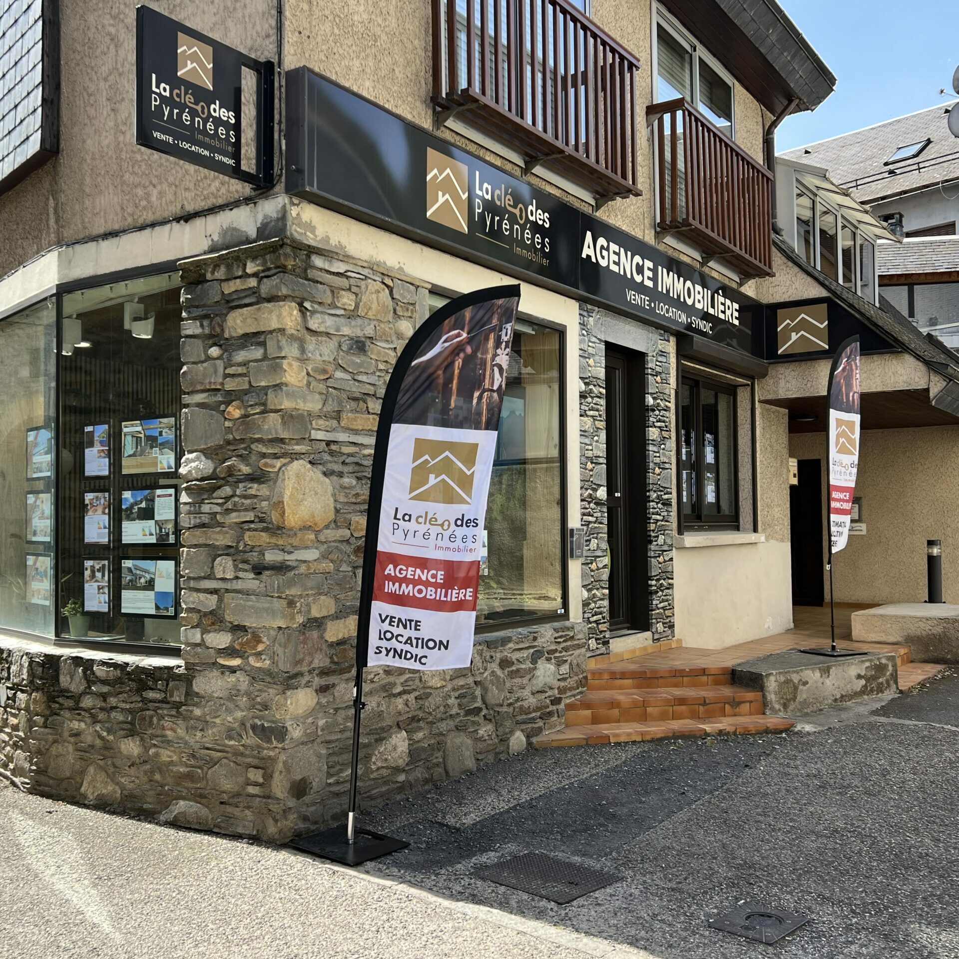 Devanture de l'agence immobilière La Clé des Pyrénées à Saint-Lary-Soulan, façade en pierre avec vitrine d'annonces