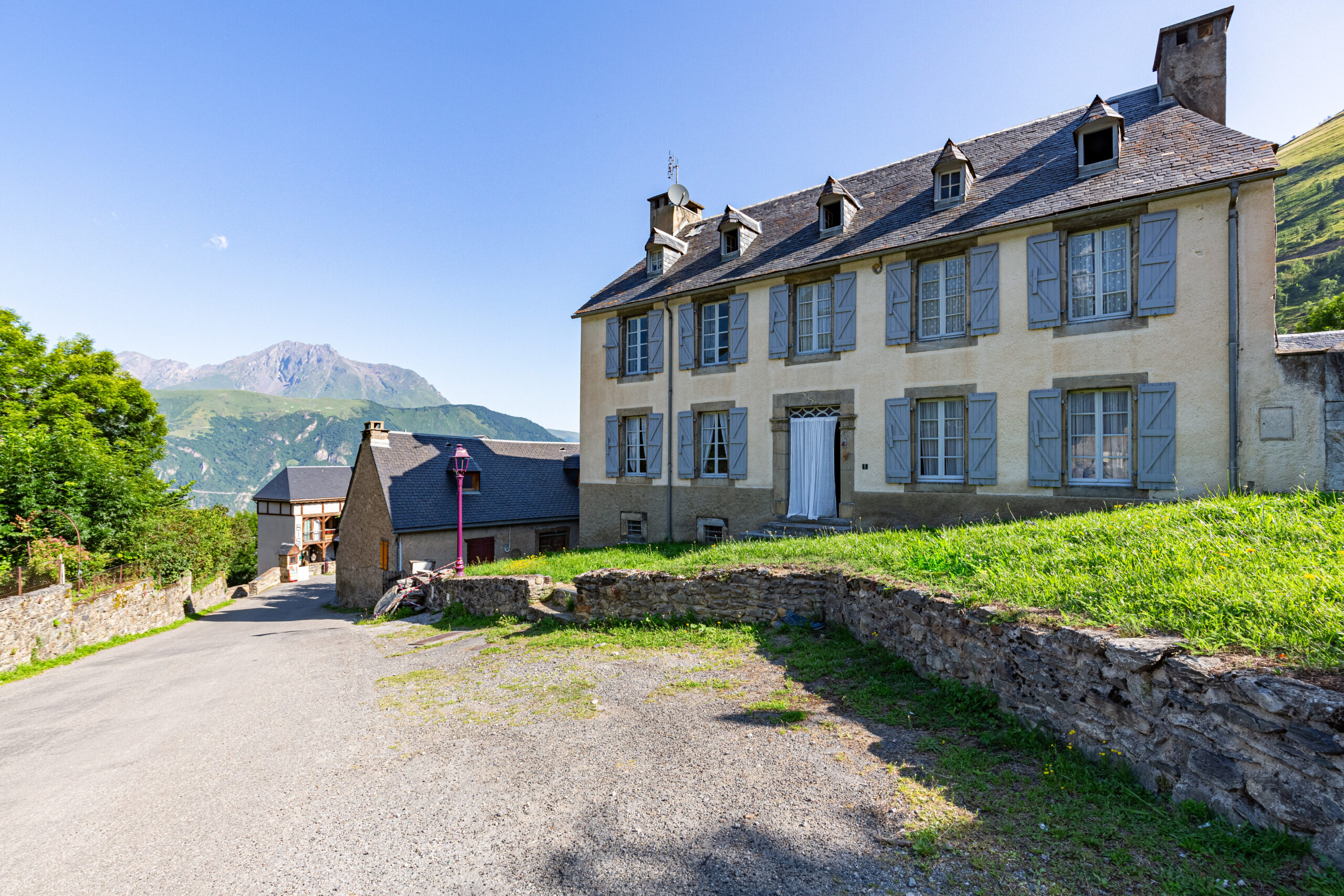 Grande maison de maître traditionnelle avec volets bleus et lucarnes, à Arreau, vue sur les sommets pyrénéens