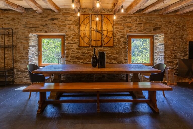 Salle à manger d'une grange rénovée avec table en bois massif, poutres apparentes et murs en pierre